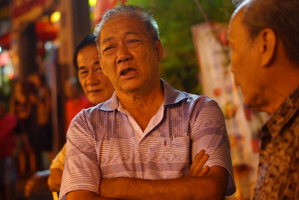 A candid shot of a man with his arms crossed on Jonker Street in Melaka, Malaysia