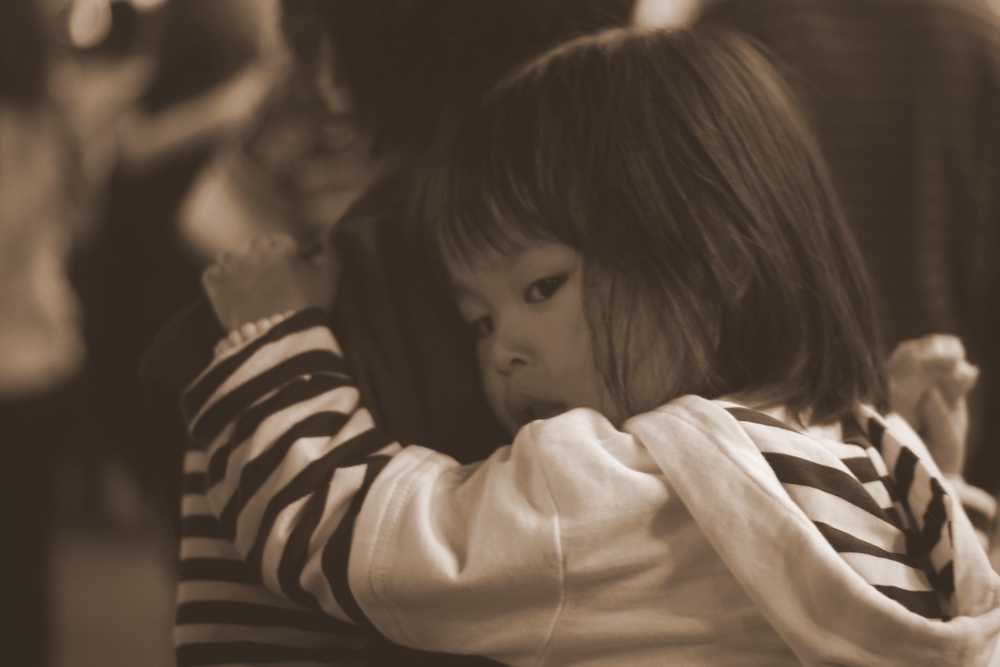 A child holds onto her mothers back as she is being carried around the market in Taipei