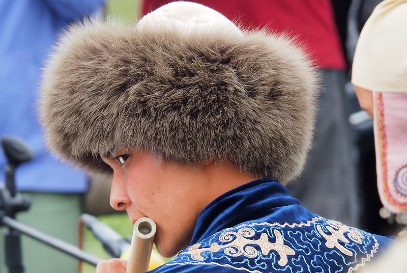 A close-up shot of a man wearing a traditional hat performing traditional Kyrgyz music at the event