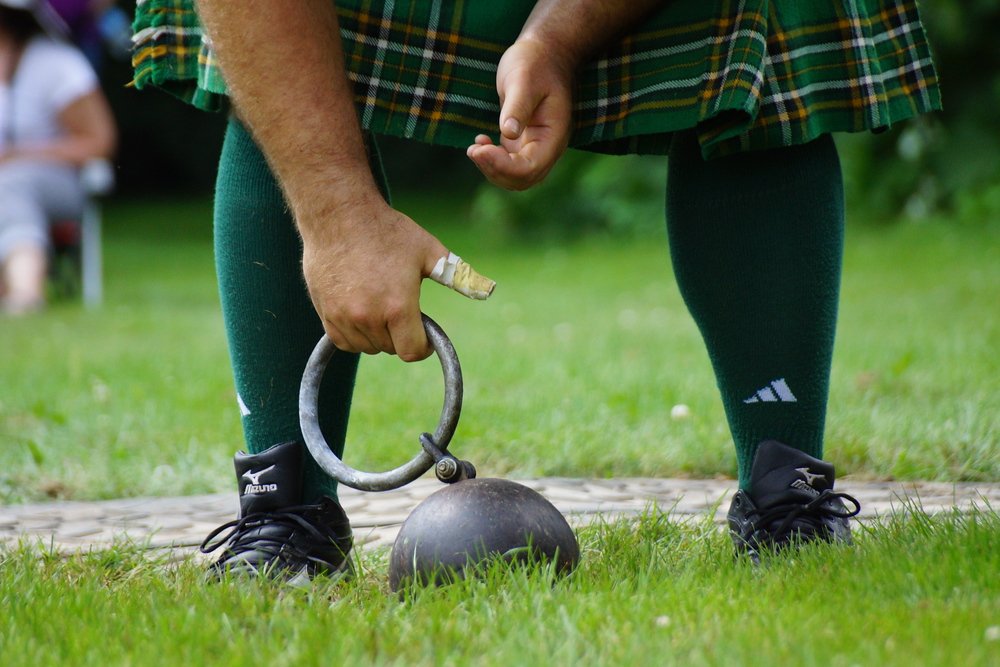 A close up shot of man bending down to pick up the handle of the weight toss at the New Brunswick Highland Games