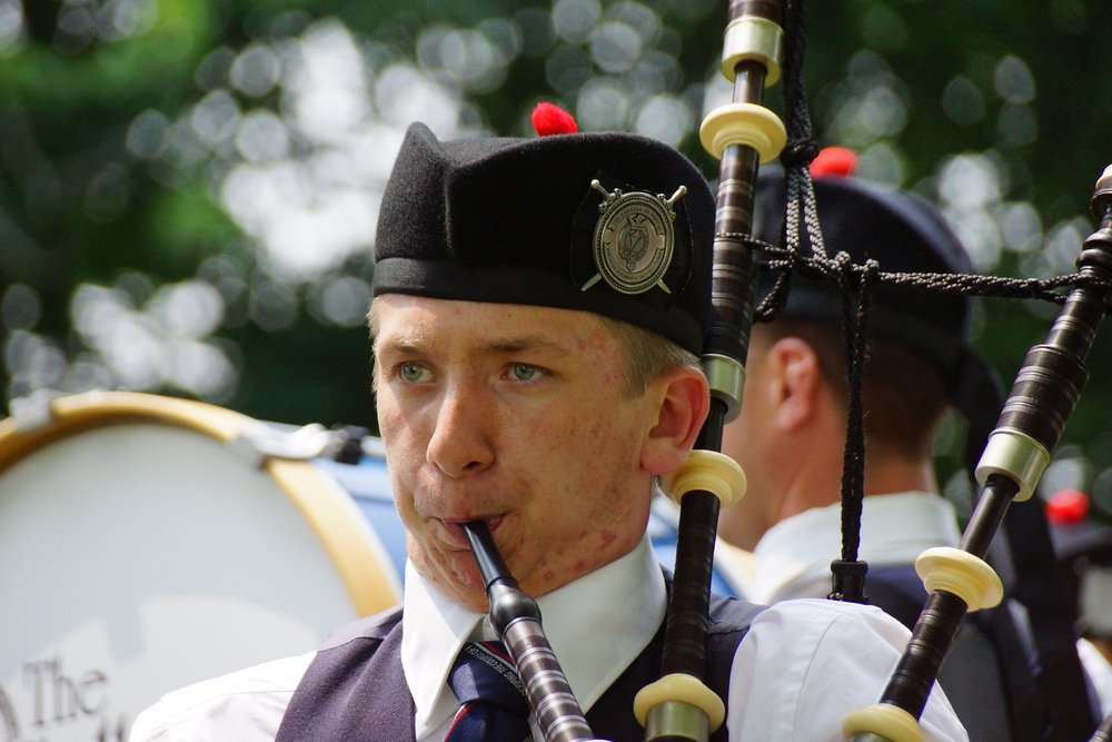 A close up shot of the face of a man blowing into the bagpipes at the New Brunswick Highland Games held in Fredericton, Canada