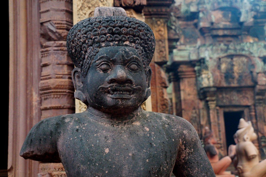 A closer up photo of a statue with its arm broken off at Banteay Srei in Cambodia 