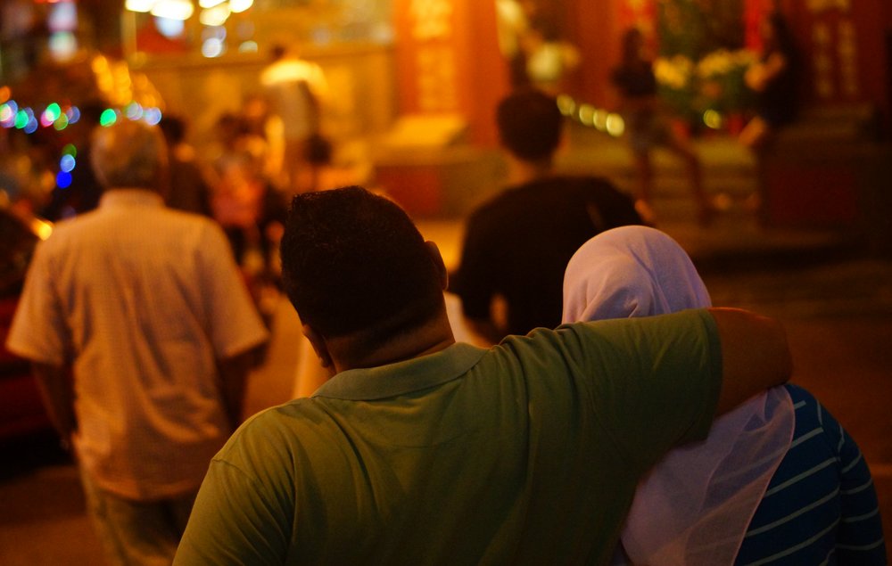 A couple embrace as they enter the night market in Melaka, Malaysia