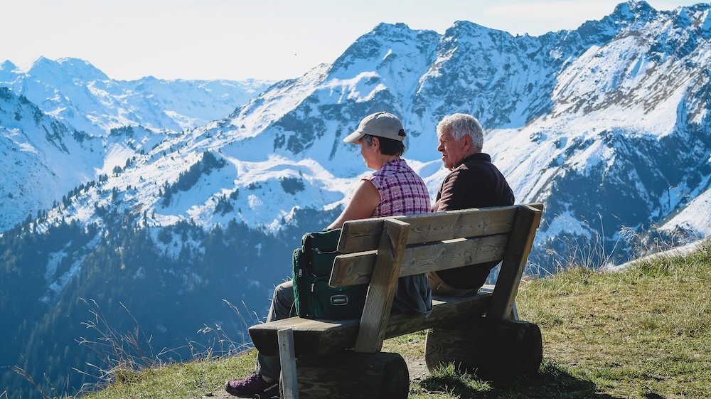 A couple taking in the icecap mountain views on a bench after Hiking in the Austrian Alps Wiedersbergerhorn in Tyrol, Austria 