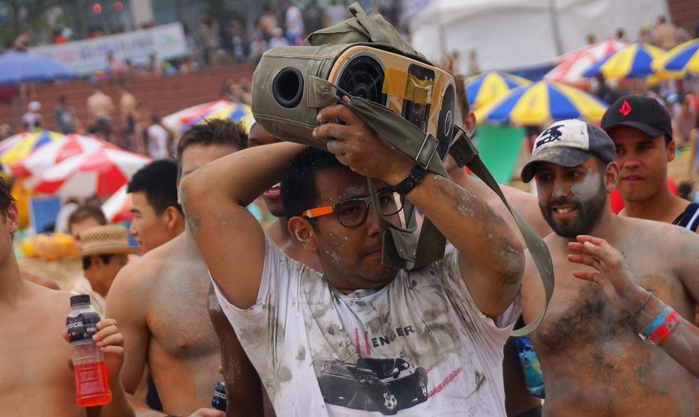 A dude carrying a random 'old school' boom box entertains the wrestling crowd with music at the Boryeong Mud Festival located in Daecheon Beach, South Korea