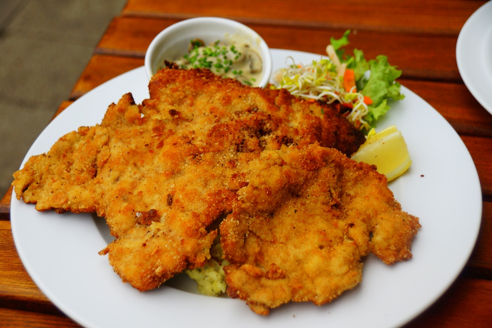 A generous portion of delicious German Schnitzel (breaded pork cutlet) for lunch on a plate in Berlin, Germany