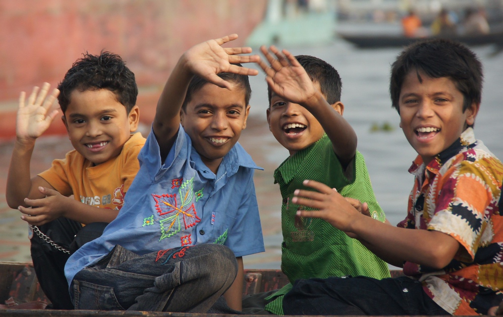 A group of adorable Bangladeshi boys wave to me as I take their photo while on a Sadarghat Boat Ride on the Buriganga River in Old Dhaka, Bangladesh