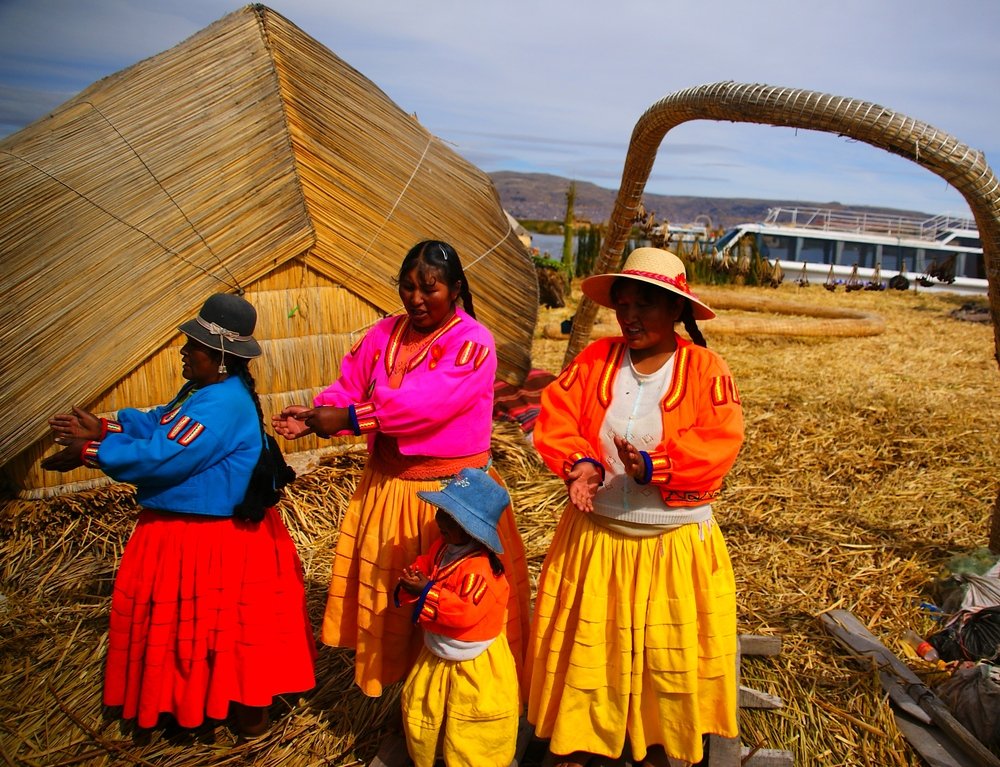 A group of gregarious Uros ladies decked out in traditional attire perform songs and dance for a group of foreign tourists. 