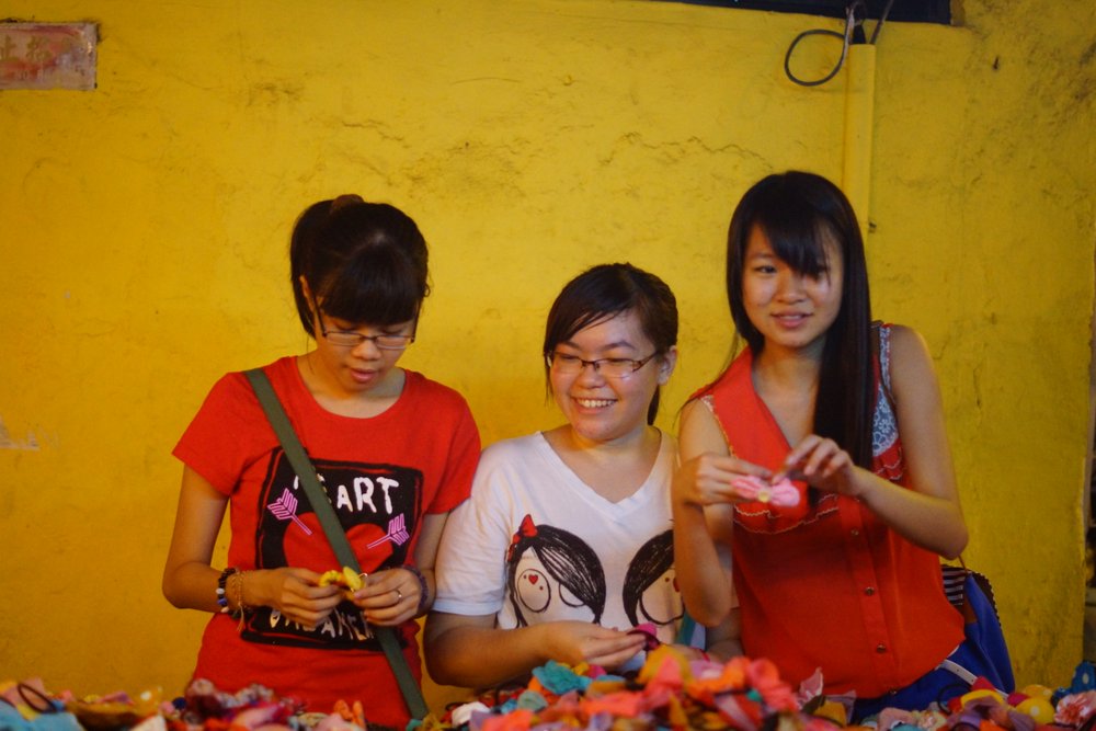 A group of ladies flash a candid smile while enjoying shopping at the night market in Jonker Street for various kinds of trinkets in Melaka, Malaysia
