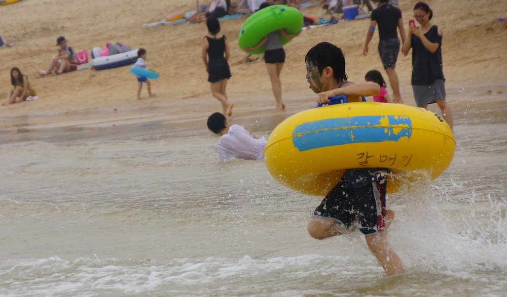 A Korean boy charges into the water with his water tube firmly gripped at the Boryeong Mud Festival event in Korea