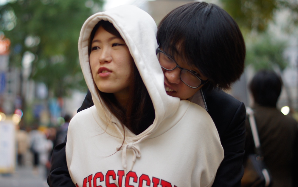 A Korean couple embrace with a hug on the street of Insadong - Seoul, South Korea
