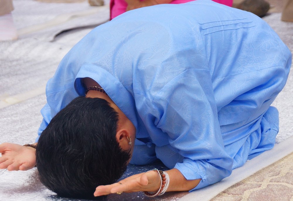 A Korean lady bows during a traditional Korean religious ceremony that was taking place mere meters away from all of the crazy festivities of the mud festival in korea