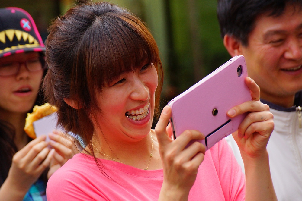 A Korean lady flashes an enormous smiling face while enjoying snapping a photo with her large pink tablet. I still find it a bit strange when seeing people taking photos with these kind of tablets - Insadong, Seoul, Korea.