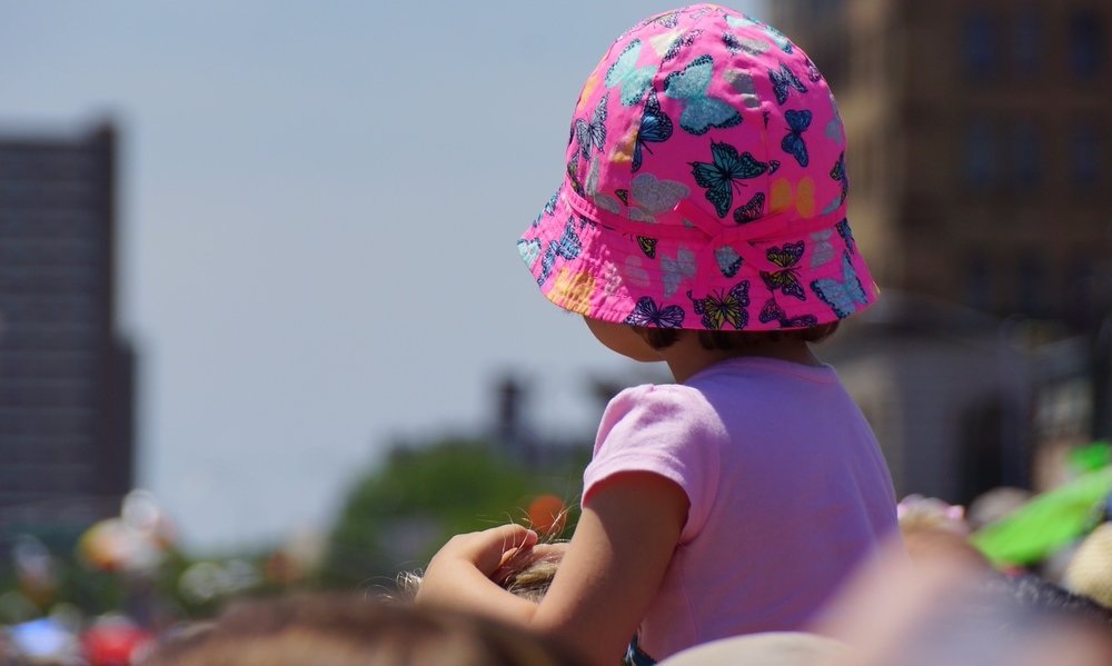 A little girl sitting on top of her Dad's shoulders watching the Coney Island Mermaid Parade