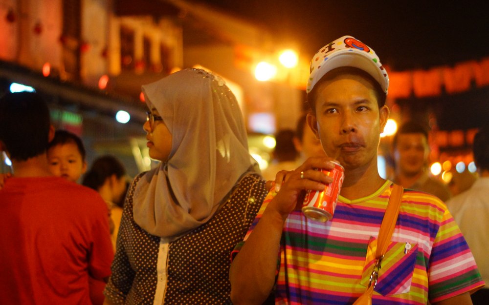 A man strolls down the main strip of the night market enjoying a refreshment along the way on Jonker Street, Malaysia