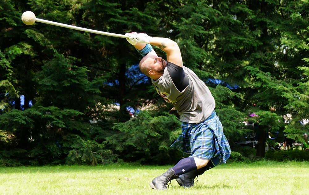 A man wielding an Ancient hammer swings it with maximum velocity over his head at the Highland Games