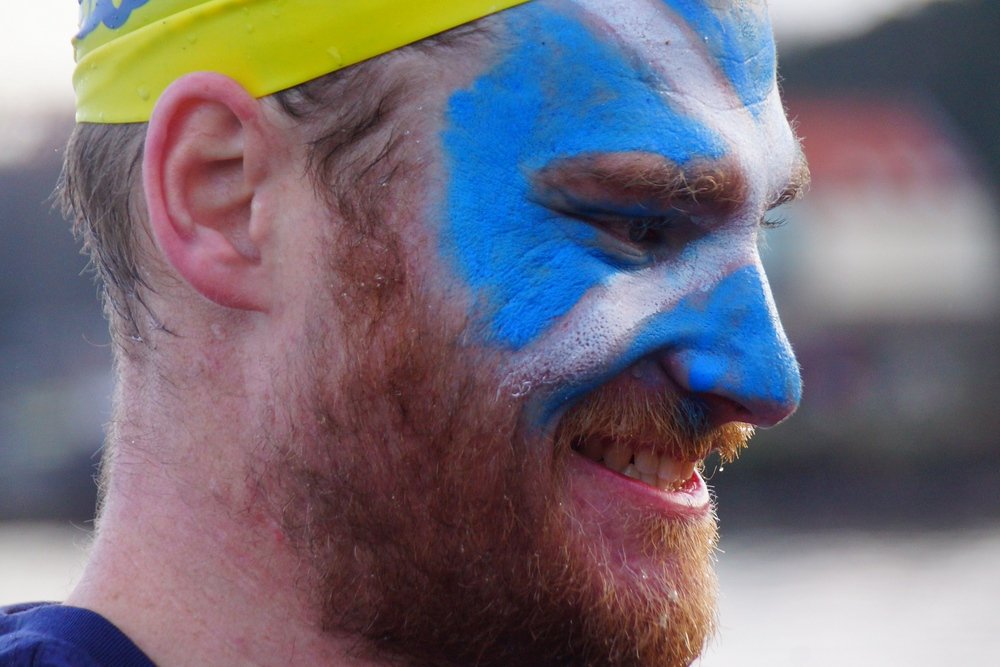 A man with the Scottish flag painted on his face stops to smile during the Loony Dook