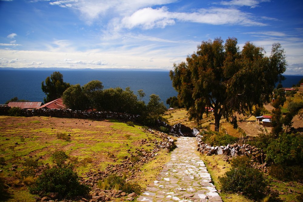 A scenic path leading down to small houses overlooking Lake Titicaca. 