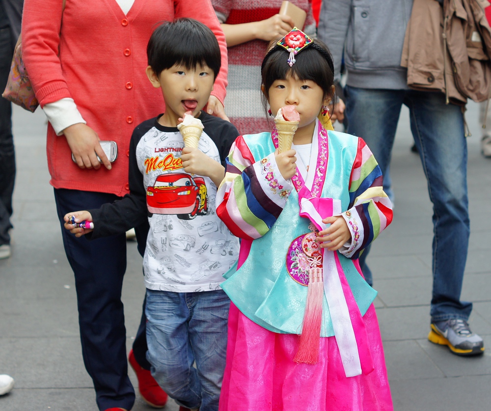 A small Korean boy and girl dressed in traditional attire enjoy a refreshing bite of an ice cream cone in Insadong, Seoul, Korea