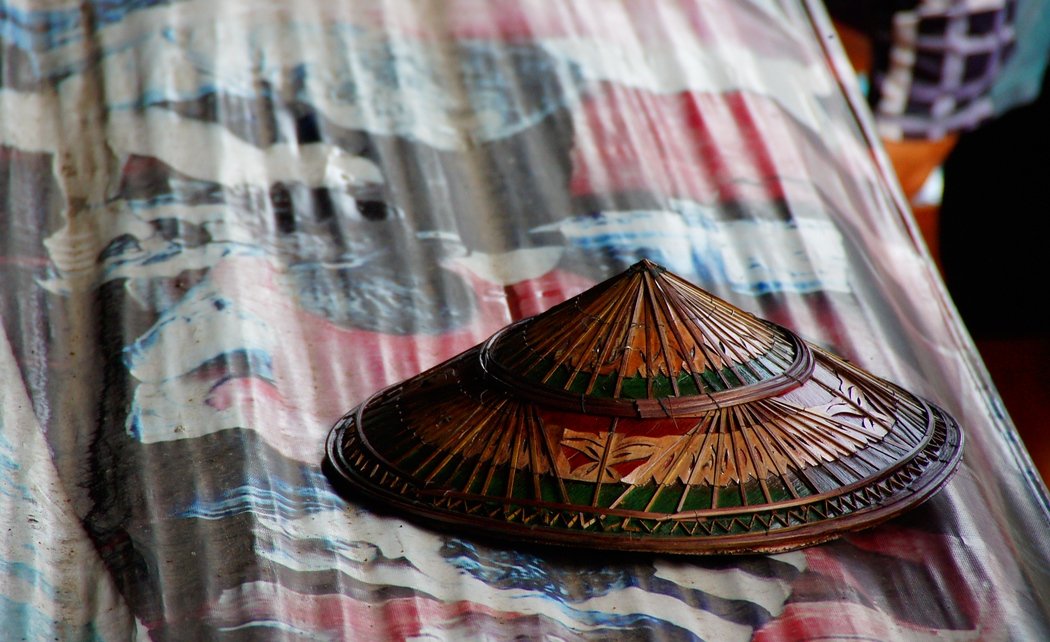 A Thai conical hat for sale on an otherwise bare display table at the Damnoen Saduak Floating Market in Bangkok, Thailand