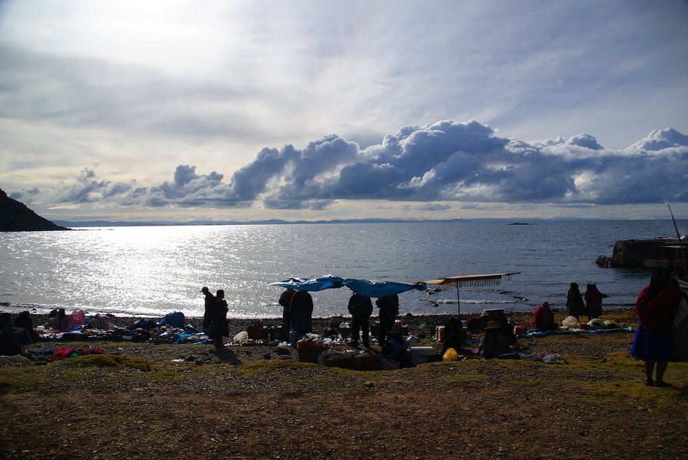 A wide angle shot of locals setting up their stalls overlooking pristine Lake Titicaca 