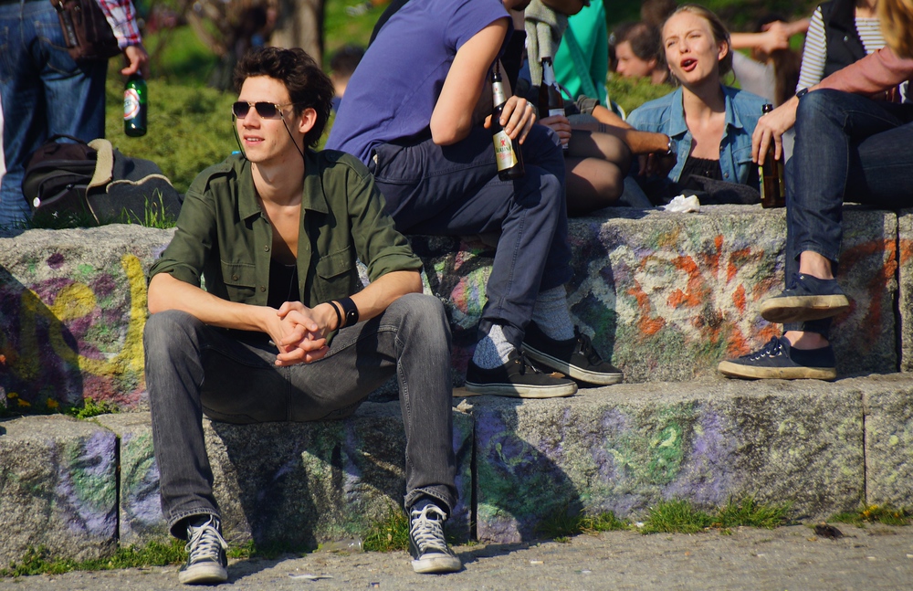 A young guy just chilling out while a group behind him share beers in Mauerpark in Berlin
