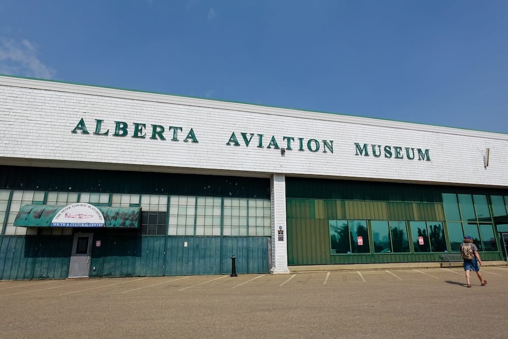 Samuel Jeffery Approaching the Alberta Aviation Museum Hangar in Edmonton, Alberta, Canada Samuel Jeffery walking toward the Alberta Aviation Museum in Edmonton, Alberta, Canada, outside the broad historic hangar marked with the museum’s name beneath a clear blue sky.