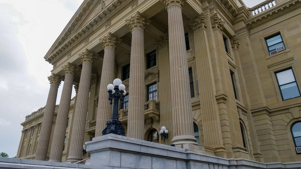Classical Columns and Entrance of the Alberta Legislature Building in Edmonton, Alberta, Canada Low-angle view of the Alberta Legislature Building in Edmonton, Alberta, Canada, showing its tall classical columns, stone facade, ornate capitals and entrance lamps beneath an overcast sky.