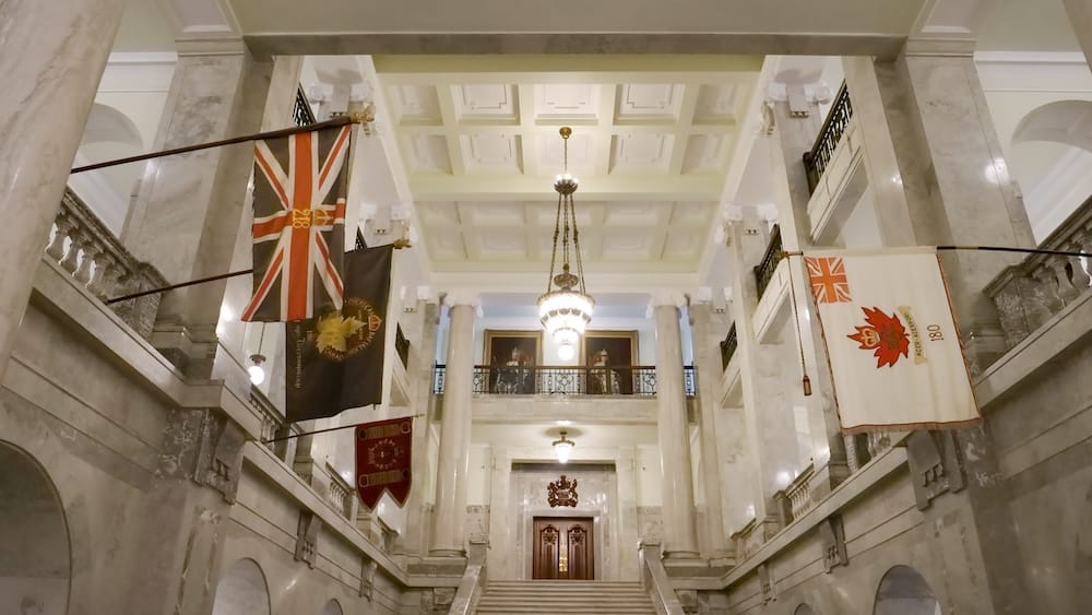 Interior del Alberta Legislature Building durante una visita guiada en Edmonton, Alberta, Canadá Interior del Alberta Legislature Building en Edmonton, Alberta, Canadá, con escaleras de mármol, columnas, arañas colgantes, banderas históricas y un salón central ornamentado durante una visita guiada.