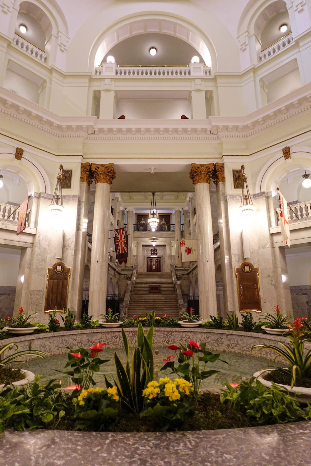 Rotonda del Alberta Legislature Building, Edmonton, Alberta, Canadá La imponente rotonda interior del Alberta Legislature Building en Edmonton, Alberta, Canadá, con columnas de mármol, una fuente central llena de flores y una escalinata amplia que sube hacia la sala principal.