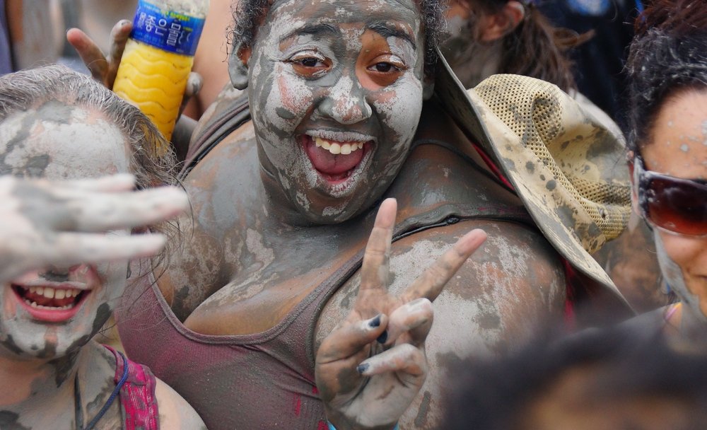 An ecstatic lady covered in mud flashes a lovely smile while posing for the camera at the Boryeong Mud Festival