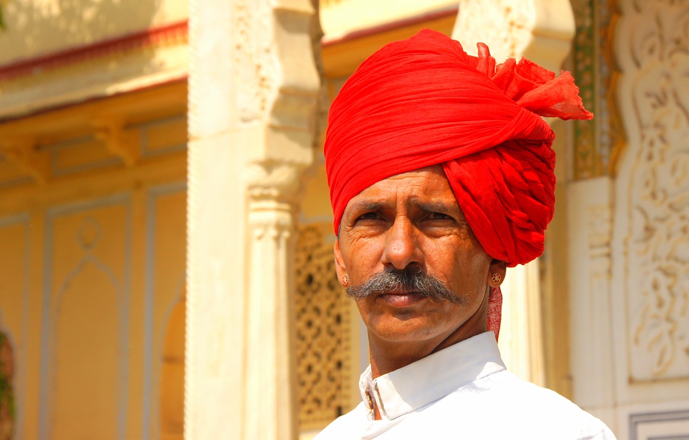 An Indian man with a distinct face and headdress poses at the Fort in Jaipur, India.