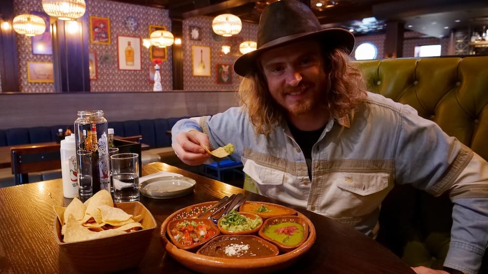 Añejo Banff chips and five salsas with Samuel Jeffery at a Mexican restaurant in Alberta, Canada Samuel Jeffery seated at Añejo in Banff, Alberta, Canada, holding a tortilla chip beside a tray of chips and five colourful salsa-style accompaniments on the table.