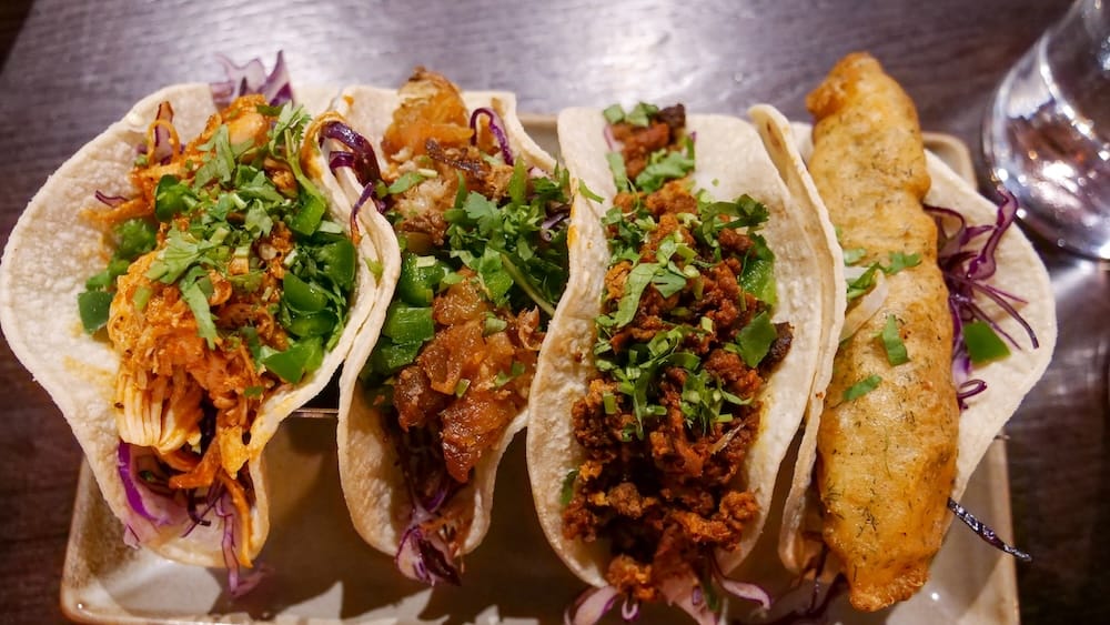 Overhead taco platter at Añejo Banff with chicken tinga, chorizo and fish tacos in Alberta, Canada Overhead view of tacos served at Añejo in Banff, Alberta, Canada, showing colourful fillings, herbs and cabbage across the chicken tinga, chorizo and fish tacos from our lunch.