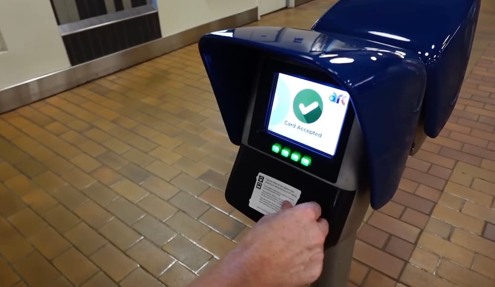Arc Fare Reader, Card Accepted, LRT Station, Edmonton, Alberta, Canada A hand taps an Arc transit card on a blue fare reader displaying "Card Accepted" at an LRT station in Edmonton, Alberta, Canada, with a tiled platform floor in the background.