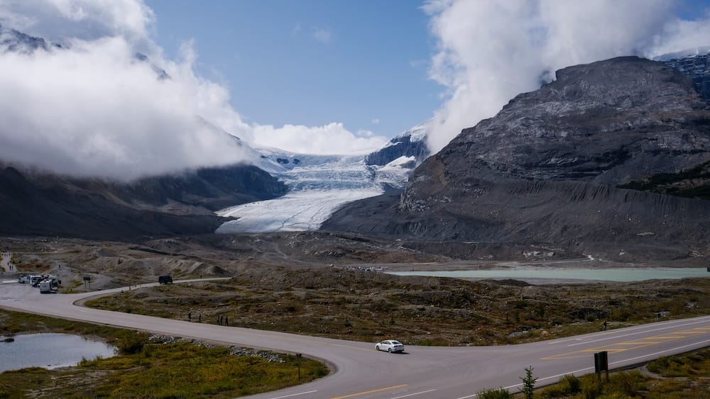 El glaciar Athabasca y el terreno montañoso de Columbia Icefield, Alberta, Canadá, vistos más allá de la Icefields Parkway y de la intersección que conduce hacia la zona de acceso al glaciar.