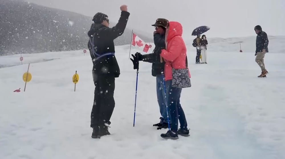 Visitantes están parados sobre el glaciar Athabasca en Columbia Icefield, Alberta, Canadá, durante una nevada intensa, con ropa de abrigo mientras la nieve y las nubes bajas reducen la visibilidad.