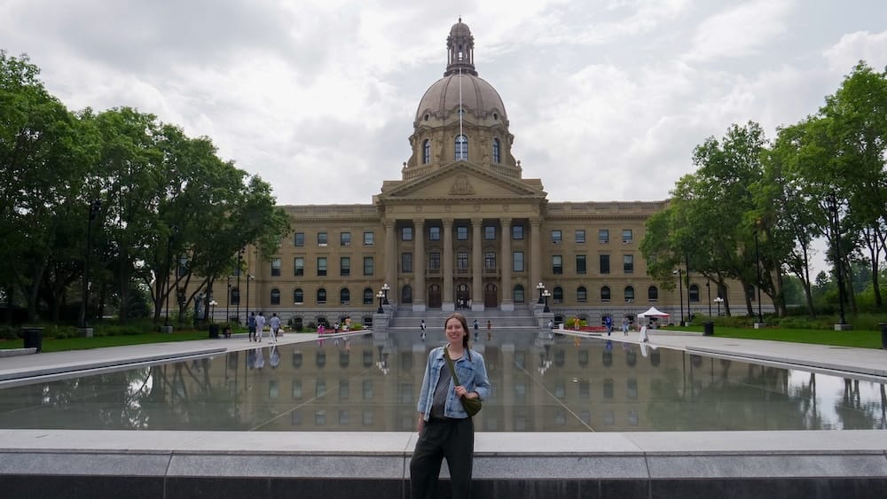 Audrey Bergner at the Alberta Legislature Building, Downtown Edmonton, Alberta, Canada Audrey Bergner stands beside the reflecting pool in front of the Alberta Legislature Building in downtown Edmonton, Alberta, Canada, with the domed facade mirrored in the water behind her.