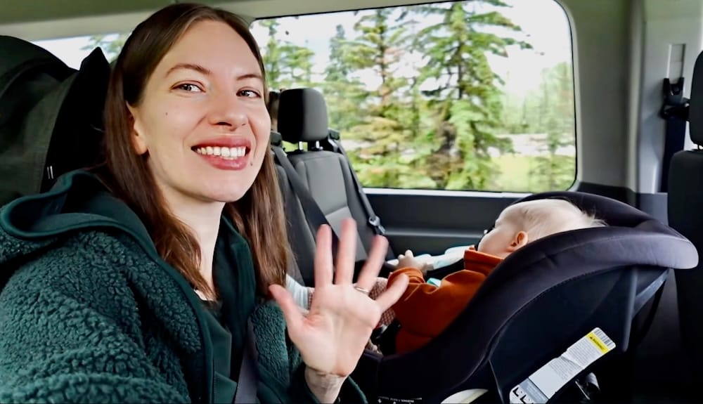 Audrey Bergner smiles and waves from inside a private tour van in Banff National Park, Alberta, Canada, with her baby daughter, Aurelia Jeffery, seated in a car seat beside her.