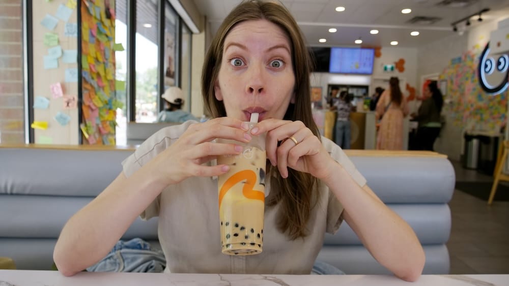 Audrey Bergner drinking a bubble tea with tapioca pearls through a straw inside CoCo Fresh Tea & Juice in Chinatown, Calgary, Alberta, Canada.