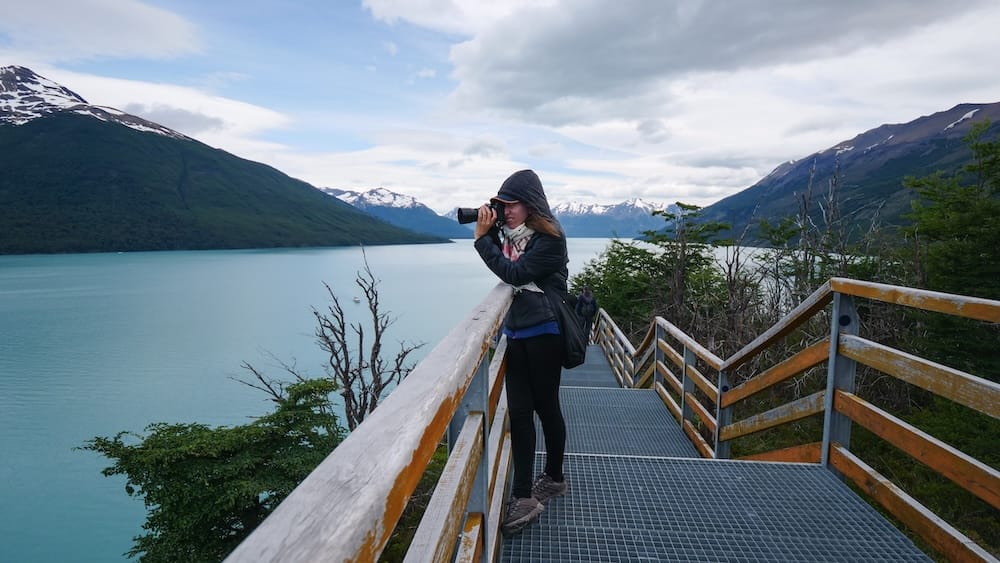 Audrey Bergner photographing Perito Moreno Glacier from the walkways in Patagonia, Argentina Audrey Bergner photographs the scenery from the Perito Moreno Glacier walkways in Los Glaciares National Park, Santa Cruz, Patagonia, Argentina, with turquoise lake water and snowcapped mountains behind her.