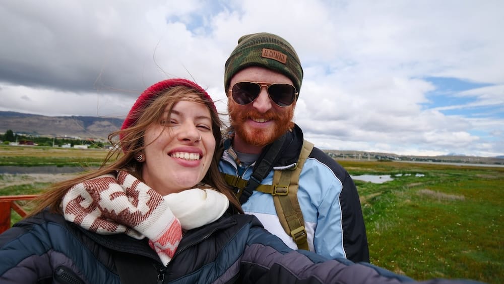 Windy Selfie Near El Calafate, Santa Cruz Province, Patagonia, Argentina — Audrey Bergner and Samuel Jeffery Audrey Bergner and Samuel Jeffery smile for a windblown selfie on the outskirts of El Calafate, Santa Cruz Province, in Argentine Patagonia, hair whipping across their faces under a wide, cloud-streaked sky with the steppe and distant mountains behind them.