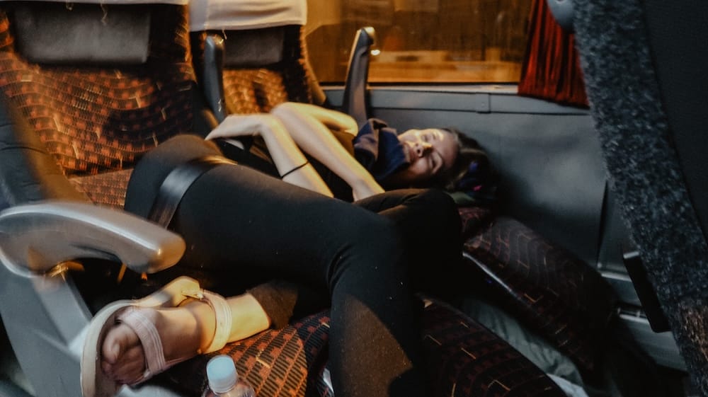 Audrey Bergner Sleeping on an Overnight Bus to Puerto Madryn, Patagonia, Argentina Audrey Bergner sleeps across padded seats inside a long-distance bus during an overnight journey to Puerto Madryn, Chubut, Patagonia, Argentina, with her legs stretched between the rows.