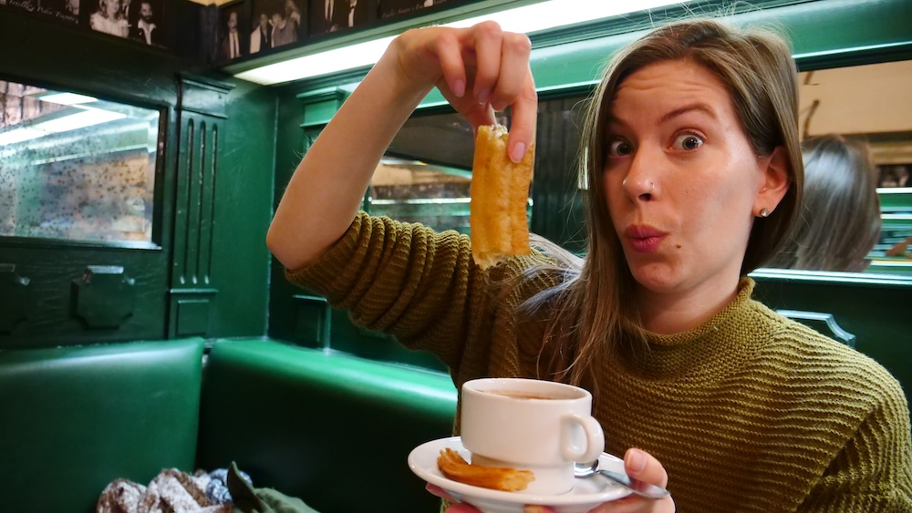Audrey Bergner aka That Backpacker showing how to eat a churros with hot chocolate in Madrid, Spain 