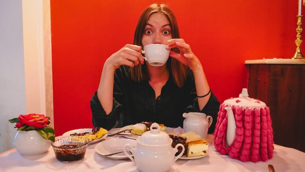 Audrey Bergner drinking tea at Ty Te Caerdydd in Gaiman Patagonia surrounded by cakes, scones, and preserves, capturing the overwhelming portion sizes and rich flavors of the traditional Welsh tea service in Argentina