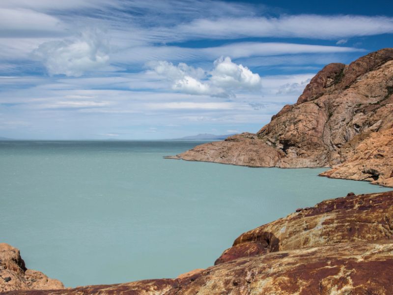 Bahía Túnel on Lago Viedma, starting point for El Chaltén glacier boat tours Bahía Túnel on Lago Viedma near El Chaltén, Patagonia, Argentina, showing turquoise glacial water, rocky shoreline, and dramatic clouds — the starting point for boat tours to the massive Viedma Glacier