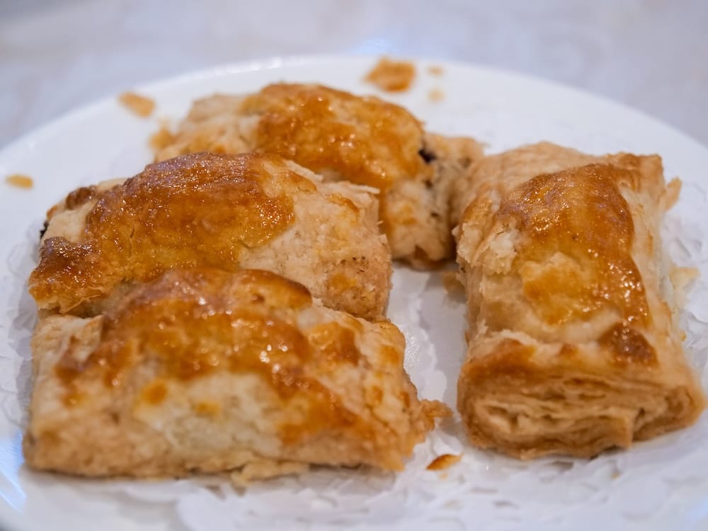 Rectangular baked barbecued pork buns with a flaky, golden-brown pastry exterior, sliced open on a plate at Chinese Cultural Centre Cuisine in Calgary, Alberta, Canada.