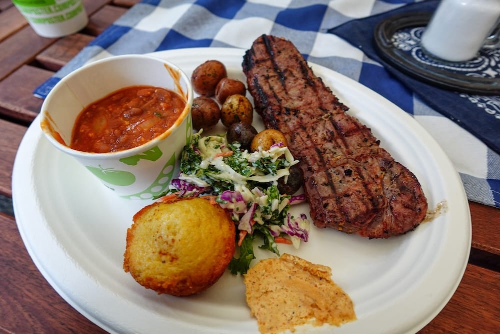 Comida completa del Banff Cowboy Cookout BBQ con steak, papas, porotos, coleslaw y pan de maíz en Alberta, Canadá Una comida completa del Cowboy Cookout BBQ en Banff, Alberta, Canadá, con steak a la parrilla, papas asadas, porotos, coleslaw y pan de maíz servidos juntos en un plato.