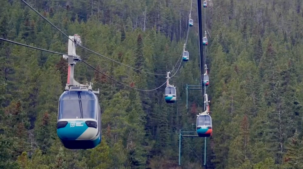 Banff Gondola cabins on the cable line up Sulphur Mountain, Banff, Alberta, Canada A line of Banff Gondola cabins travels along the cable up Sulphur Mountain, suspended above dense evergreen forest near Banff, Alberta, Canada.