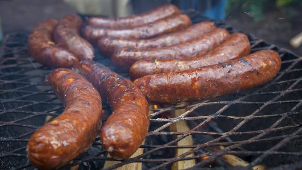Salchichas a la parrilla durante una comida de Banff Trail Riders en el Parque Nacional Banff, Alberta, Canadá Varias salchichas se cocinan sobre una parrilla al fuego durante una parada de comida de Banff Trail Riders en el Parque Nacional Banff, Alberta, Canadá, con humo elevándose alrededor de las piezas doradas.